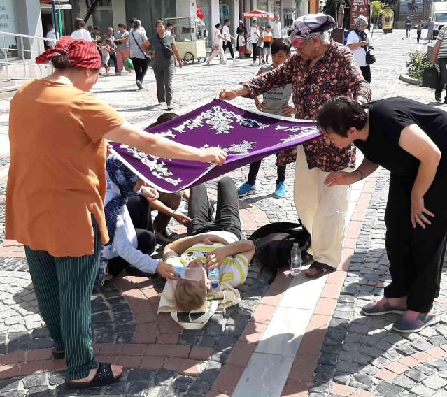 Kadınlar yerde yatan yaralıyı örtü ile güneşten korudu